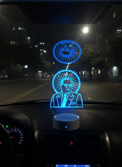 Blue LED light display on a car dashboard with a face design.
"Blue LED 3D illusion lamp of Dr. B. R. Ambedkar with the Ashoka Chakra, sitting on a car dashboard at night"
LED illusion lamp, Dr. B. R. Ambedkar, Ashoka Chakra, car dashboard decor
Babasaheb Ambedkar, Indian Constitution, blue LED idol, vehicle dashboard.

"Blue glow-in-the-dark B. R. Ambedkar light