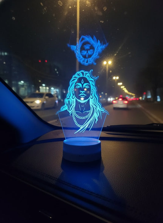 "Blue LED 3D illusion light of Lord Shiva (Mahadev) with crescent moon and cobra, placed on a car dashboard at night"
LED illusion light, Lord Shiva, Mahadev, car dashboard decor, cobra.
"Glowing blue Shiva Mahadev idol on car dash, offering protection and positive energy for safe night driving"
Shiva Mahadev idol, car dash, protection, night driving.