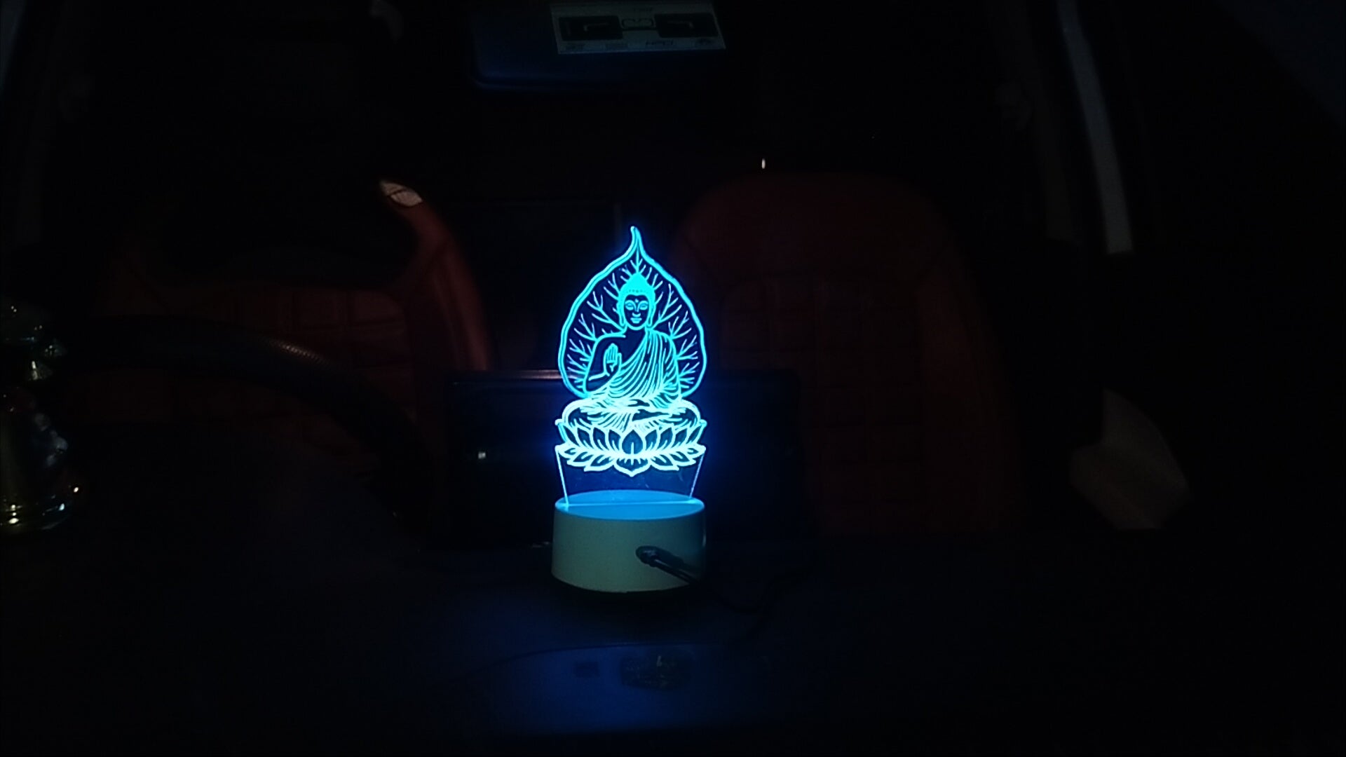 Gautam Buddha 3D illusion LED lamp glowing in blue light, placed on a car dashboard for spiritual car decor"
"Blue light Buddha LED lamp for car interior, perfect for peace and positive energy while driving"
"Spiritual 3D LED Buddha lamp illuminating a vehicle dashboard, ideal for meditation lovers and car decor"
"Glow X Art's Gautam Buddha acrylic illusion lamp glowing at night inside a car"Peaceful Buddha 3D night light for car dashboard with soft LED glow in blue tone"
"Laser-cut acrylic Buddha LE